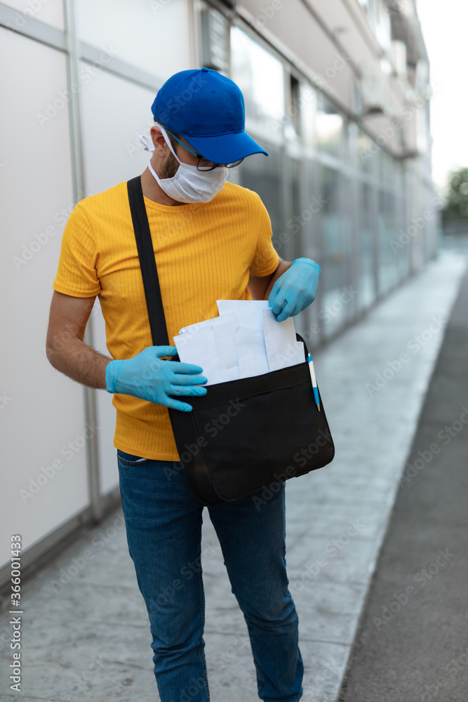 Mailman delivering mail with mail-bag and protective mask and gloves during virus pandemic. Mailman delivering mail with mail-bag and protective mask and gloves during virus pandemic.