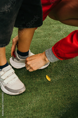 woman straightens sneakers for a child
