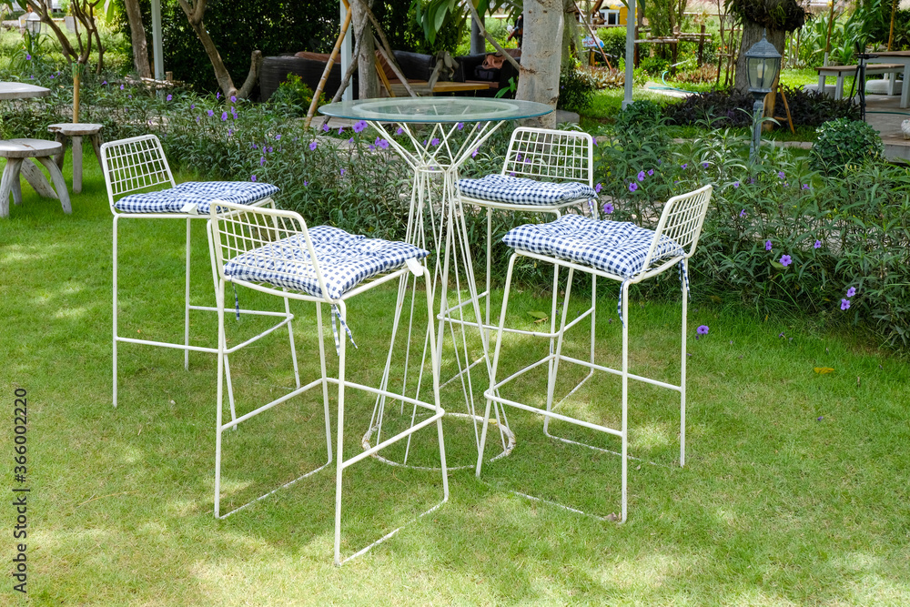 set of white metal coffee table with tall chairs with blue striped cushion in a beautiful garden,Patio furniture set of white metal coffee table with tall chairs with blue striped cushion in a beautiful garden,Patio furniture