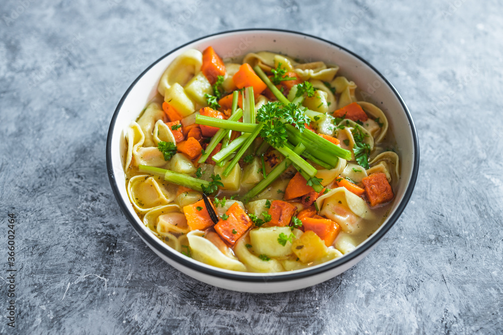 plant-based food, vegan ravioli pasta with vegetable broth topped with pumpkin and sweet potato cubes and celeri sticks plant-based food, vegan ravioli pasta with vegetable broth topped with pumpkin and sweet potato cubes and celeri sticks