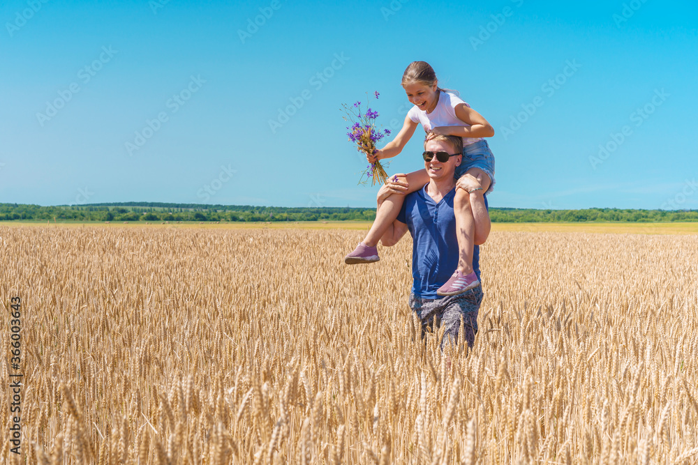 Happy beautiful father dad carries a little beautiful child girl on his shoulders, free time. Family entertainment in a wheat field Happy beautiful father dad carries a little beautiful child girl on his shoulders, free time. Family entertainment in a wheat field