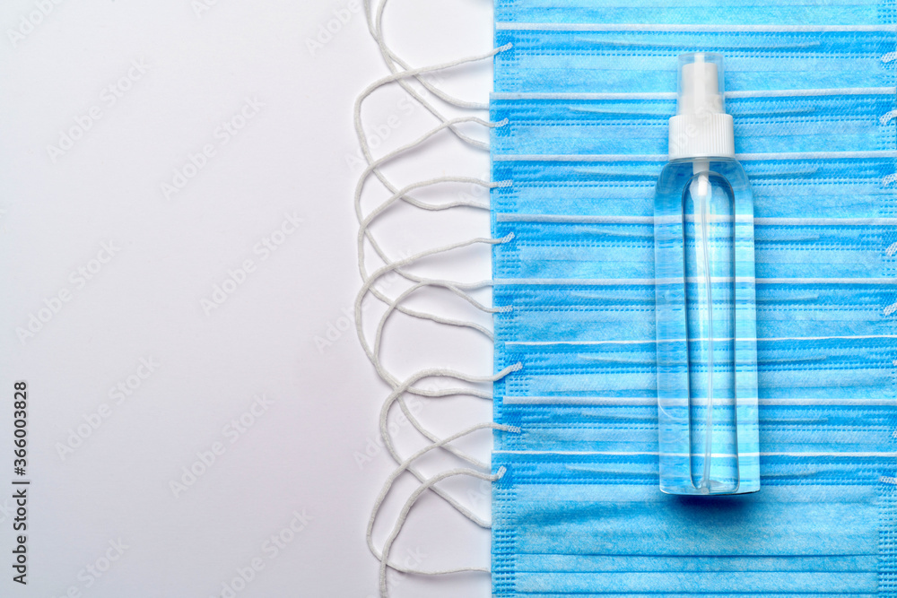 bottle of lotion, sanitizer or liquid soap and protective mask over light grey background bottle of lotion, sanitizer or liquid soap and protective mask over light grey background
