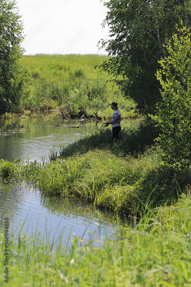 a man fishing on the river, a fisherman on the river Bank stands with a fishing rod in hope a man fishing on the river, a fisherman on the river Bank stands with a fishing rod in hope