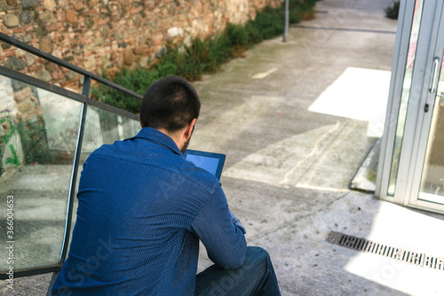 Bearded man sitting on steps while using a tablet © Rafa Fernandez