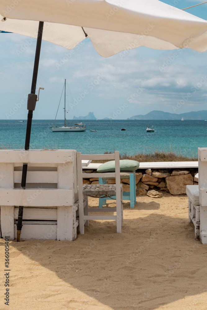 Impressive view of the turquoise sea and crystal clear water on the beach of Ses Illetes in Formentera Island, one of the Balearic Islands, from a typical chiringuito bar. Mediterranean summer.