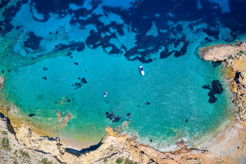 Fototapeta premium Aerial top down view to a little bay on Patroklos island, close to Sounion, south Attica, Greece, with moored boats enjoying the emerald sea during summer time