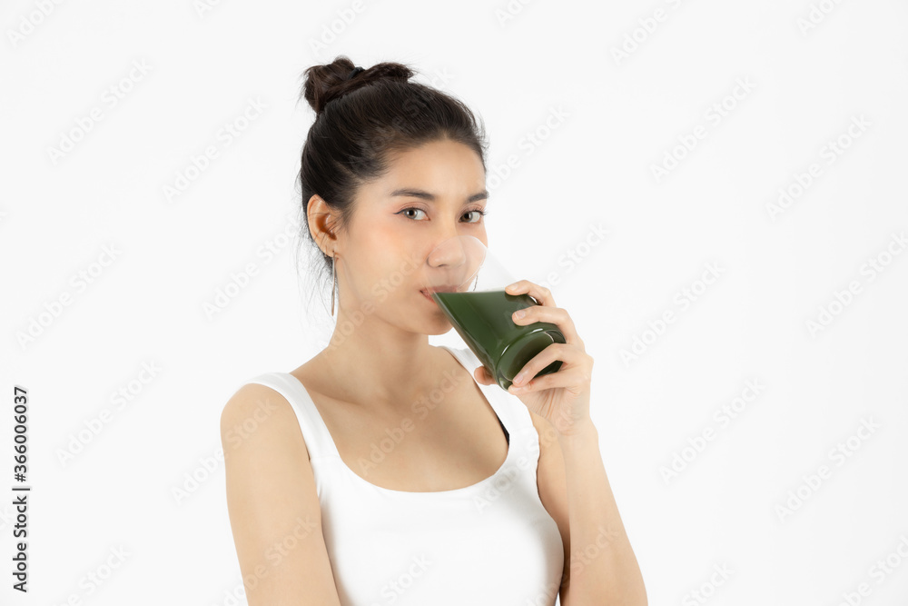 Healthy young Asian woman drinking green detox vegetable smoothie over white isolated background. Vegetarian drink juice, Healthy lifestyle, Fitness and health care concept. Healthy young Asian woman drinking green detox vegetable smoothie over white isolated background. Vegetarian drink juice, Healthy lifestyle, Fitness and health care concept.