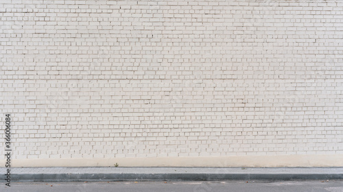 spacious white empty brick cracked wall background on sidewalk of city street