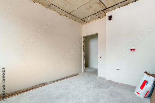 The corner view an unfinished apartment room with the empty doorway and the plastered walls