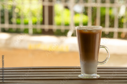 Closeup one glass with ice latte on wooden table. Selective focus