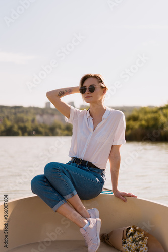 Pretty amazing young woman  blond relaxing on a boat  wearing sunglasses  enjoying her vacation  camomile flowers and amazing time