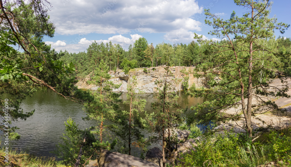 Panorama of forest lake with rocky shores through the trees
