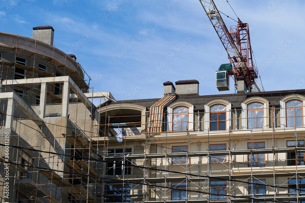 modern building under construction, plastered walls and scaffolding, construction crane