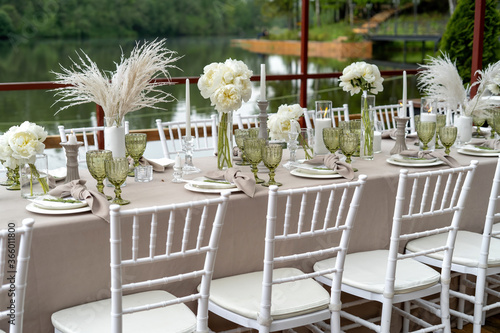 Decorated wedding table, white peonies and feathers. Chiavari chairs are at the table-2. photo