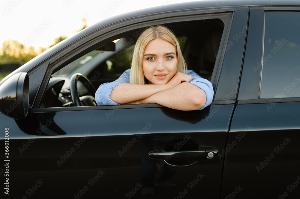 Female student poses in car, driving school