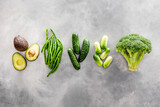 Green vegetables background. Сucumber, avocado, broccoli, beans, leek and fresh apple on grey stone background top view mockup