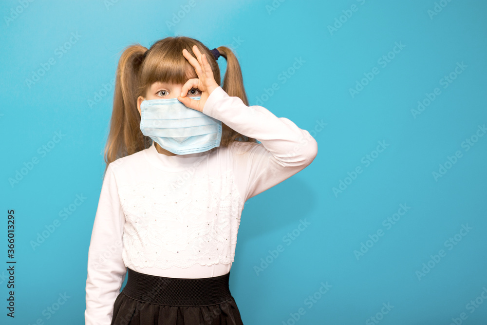 Little girl wearing medical mask show symbol OK finger hands gesture for stop corona virus outbreak isolated on blue. Little girl wearing medical mask show symbol OK finger hands gesture for stop corona virus outbreak isolated on blue.