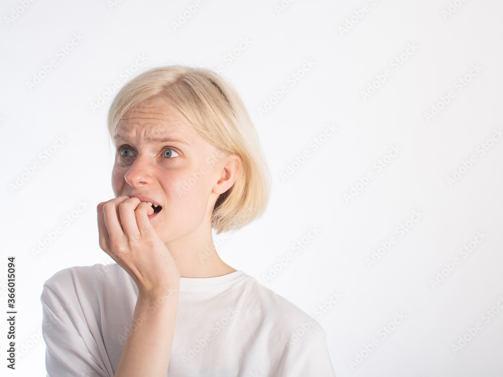 a young blonde girl in a white t-shirt bites her fingernails due to stress/excitement. isolate on white. space for text a young blonde girl in a white t-shirt bites her fingernails due to stress/excitement. isolate on white. space for text