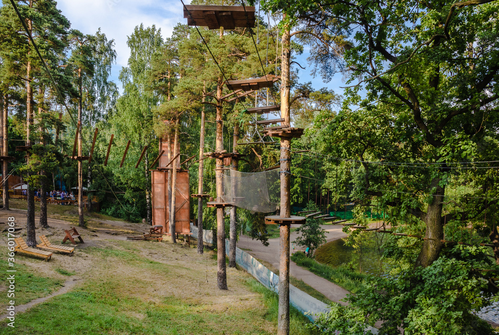 On high pines various equipment and gear for sports - ropes, slings, wooden steps, grids, platforms is fixed On high pines various equipment and gear for sports - ropes, slings, wooden steps, grids, platforms is fixed