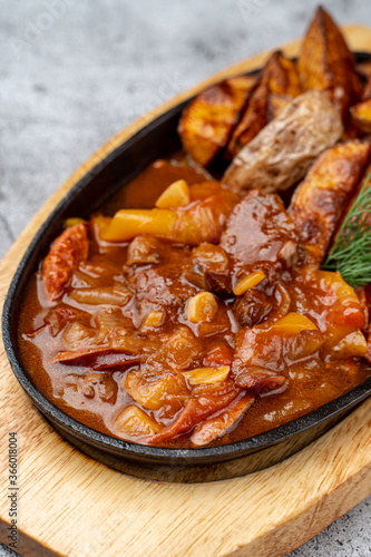 Close up of meat and potato ragout in red sauce in cast-iron skillet