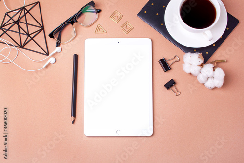 White tablet, glasses, notebook and coffee on a beige background. Concept of online learning, distant work