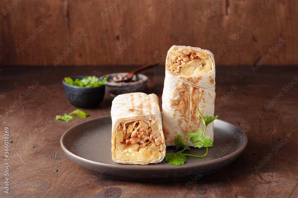 A cut Chicken doner kebab in roll of pita bread lavash. Shawarma Sandwich on a wooden background