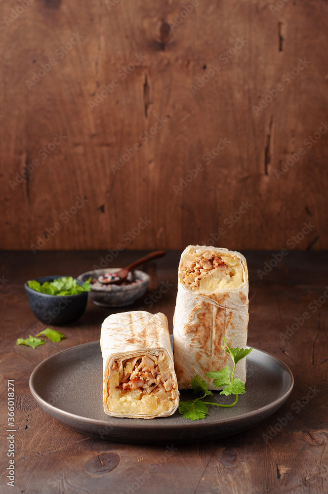 A cut Chicken doner kebab in roll of pita bread lavash. Shawarma Sandwich on a wooden background