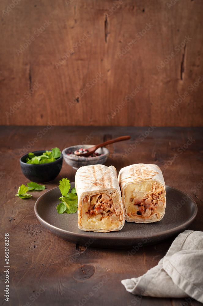A cut Chicken doner kebab in roll of pita bread lavash. Shawarma Sandwich on a wooden background