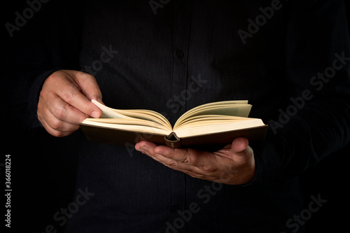 Person reading a book on a dark background. Concept education
