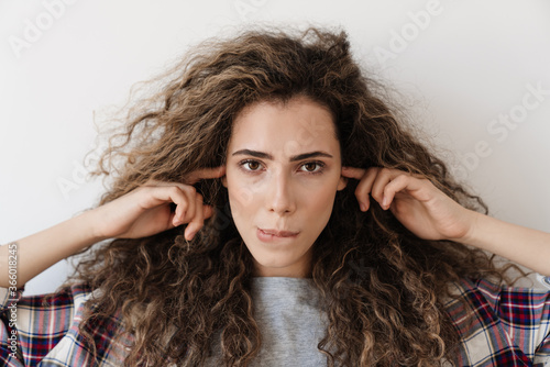 Photo of young woman plugging her ears while posing on camera