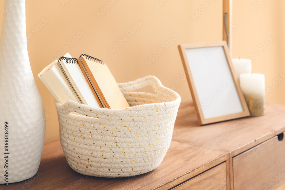Wicker basket with notebooks on table in room Wicker basket with notebooks on table in room