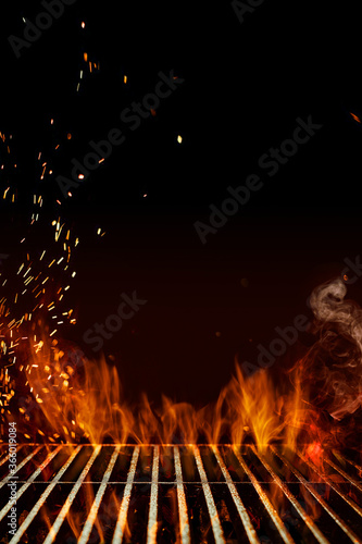 Obraz na płótnie Empty steel barbecue BBQ grill grate with flaming fire, sparks and smoke on black background. Cooking concept. Close up, copy space w salonie