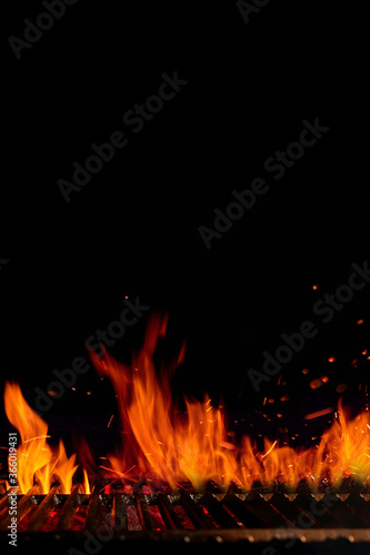 Obraz na plátně Empty hot barbecue BBQ grill grid with burning fire, sparks and smoldering charcoal on black background
