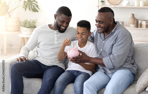 Smiling African Father And Grandfather Teaching Preteen Boy Savings And Financial Planning