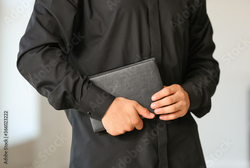 Male priest with Bible at home