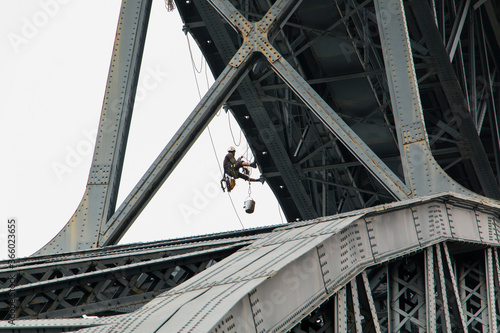 Painter working on the Porto Bridge. A worker repairs the Porto bridge hanging by ropes