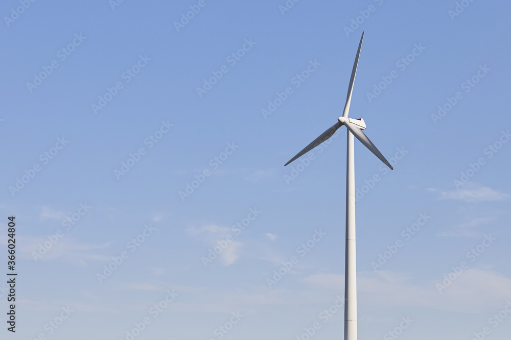 Wind turbine on the green grass over the blue clouded sky. Protection of nature. Wind turbine - renewable energy source. Wind turbine on the green grass over the blue clouded sky. Protection of nature. Wind turbine - renewable energy source.