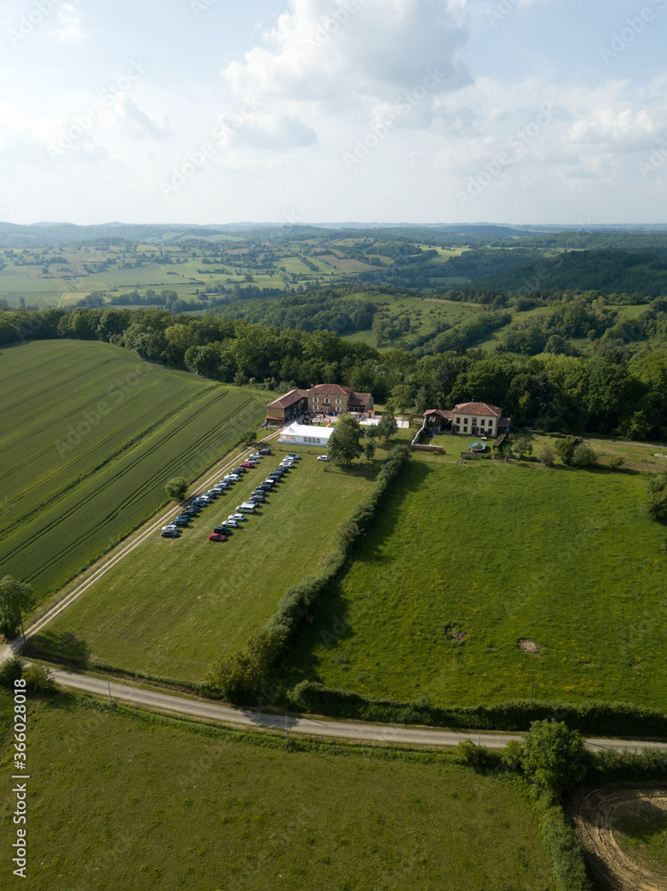 Sarremezan, France. Aerial rural landscape from above, road between green fields and meadows Countryside european village buildings private houses cloudy sky summer