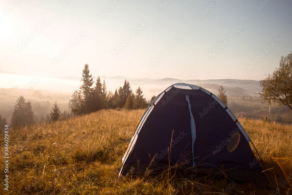 Morning landscape in mountains with tent. Camp rest in forest