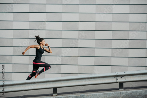Speed and run. Athletic african american girl in sportswear, runs on street