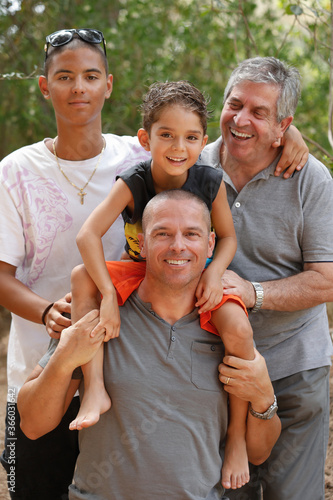 Papà e Nonno bianchi e figli Italo- brasiliani uniti in un abbraccio sorridono felici , isolati su uno sfondo di natura photo