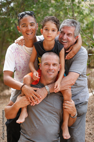 Papà e Nonno bianchi e figli Italo- brasiliani uniti in un abbraccio sorridono felici , isolati su uno sfondo di natura photo
