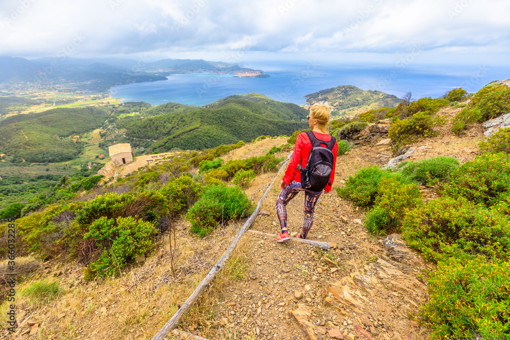 Hiking to Volterraio Castle. Backpacker woman looking views of Portoferraio Gulf, Elba Island. Stone stairs along Monte Volterraio with medieval fortress dominates.Tourism in Tuscany Italy destination