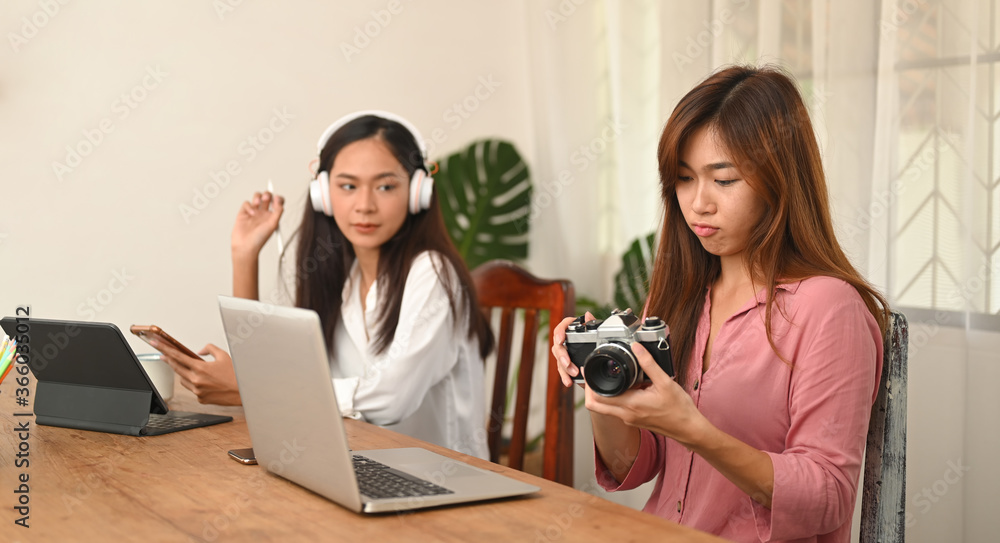 Photographer Women are working together with a computer tablet and laptop at the wooden working desk. Photographer Women are working together with a computer tablet and laptop at the wooden working desk.