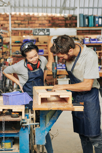 Obraz na plátně Carpenter showing female apprentice how to assemble wooden drawer
