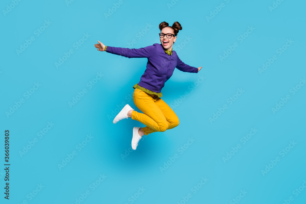 Full body profile photo of crazy lady two buns jump high celebrate vacation holidays weekend rejoicing spread arms wear specs shirt pullover pants isolated blue color background