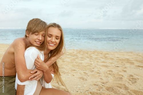 Family On Beach. Mother With Kids Enjoying Summer Vacation At Coast. Handsome Son Hugs Young Woman. Family Weekend With Children For Happy Childhood. © puhhha