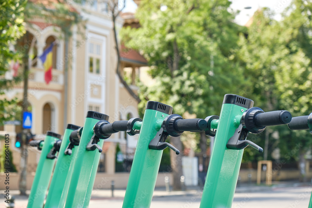 Row of green-blue electric scooters, a cleaner, modern alternative transportation option in cities. Close up.