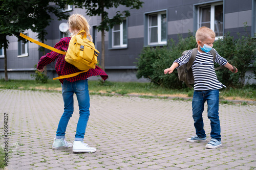 back to school. children playing on street. Kids wearing mask and backpacks protect and safety coronavirus. Boy and girl going school after pandemic over © Наталия Кузина