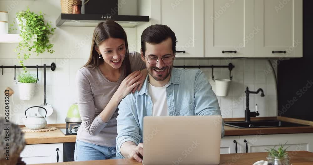 Spouses spend time on rented home kitchen look at pc screen laughing receive e-mail from bank feels excited, loan accept, on-line betting win, lottery victory. Moment of sincere happy emotions concept Spouses spend time on rented home kitchen look at pc screen laughing receive e-mail from bank feels excited, loan accept, on-line betting win, lottery victory. Moment of sincere happy emotions concept